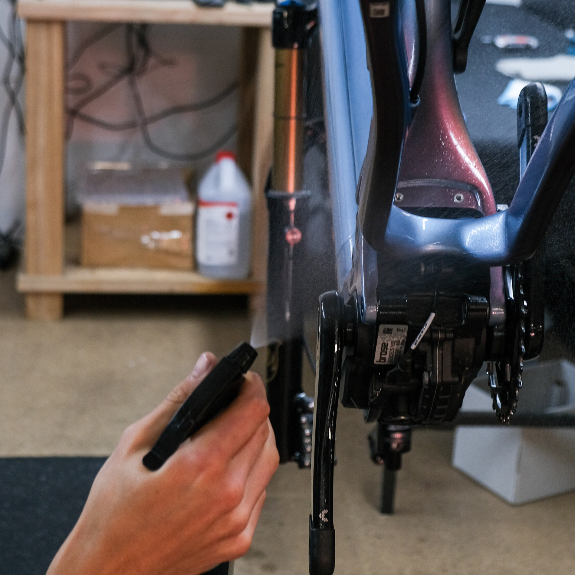 Close-up of person spraying down a bike frame before frame protection is applied.