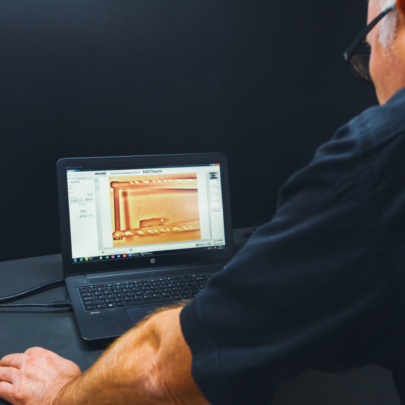 Person using a laptop with thermal imaging software on a dark background