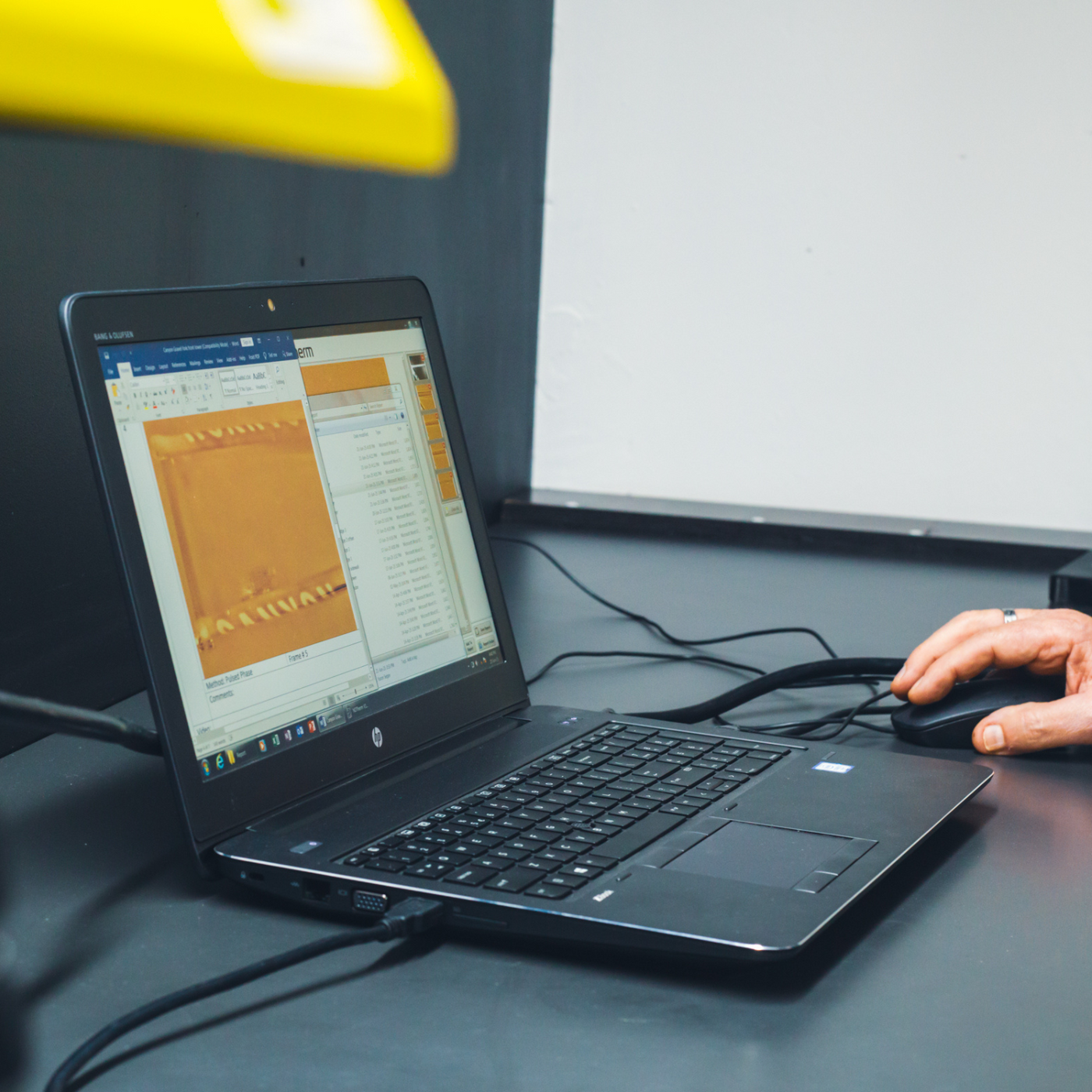 Person using a laptop with thermal imaging software on a dark background